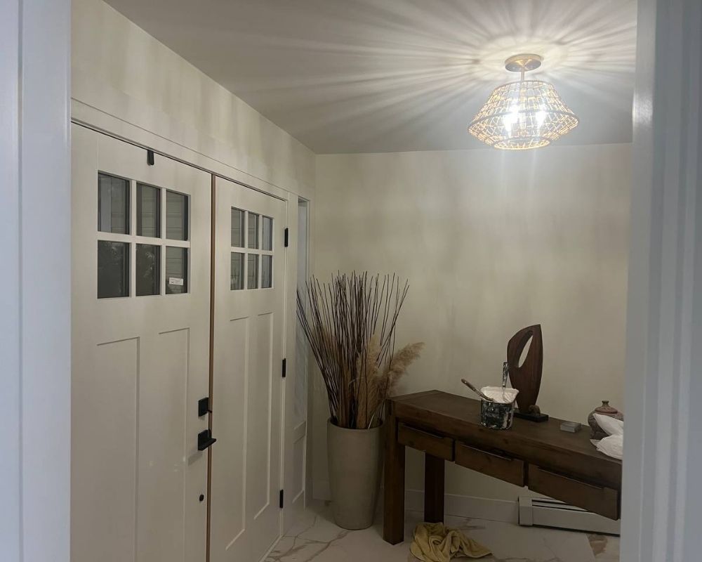 Freshly painted modern entryway in a West Vancouver home with soft white walls, double doors, and designer lighting